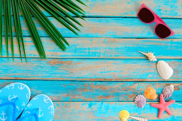Foto fundo do verão - óculos de sol, shell, estrela do mar e chinelo no fundo de madeira.