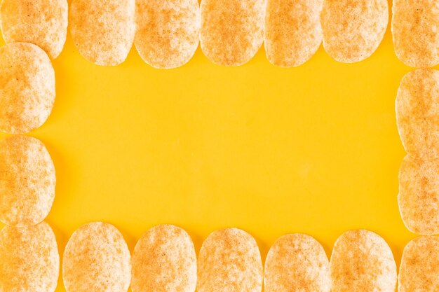Foto fundo e textura de um monte de batatas fritas giratórias sobre fundo amarelo vista de cima