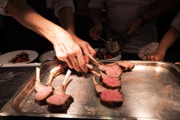 Fundo embaçado do Chef em cozinha do hotel ou restaurante cozinha com cordeiro e decoração para o jantar de luxo.