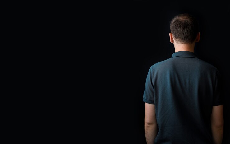 Foto fundo escuro com um homem. espaço livre para texto ou logotipo, copie o espaço. pessoa sobre o fundo preto, mostrando algo com uma mão. apenas visível de volta. template moderno