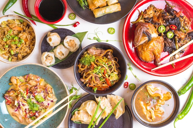 Fundo escuro de comida chinesa. Macarrão chinês, arroz, bolinhos, pato laqueado, dim sum, rolinhos primavera