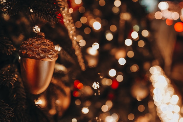 Fundo festivo com lindas luzes douradas do bokeh Brinquedo de Natal ramos de bolota