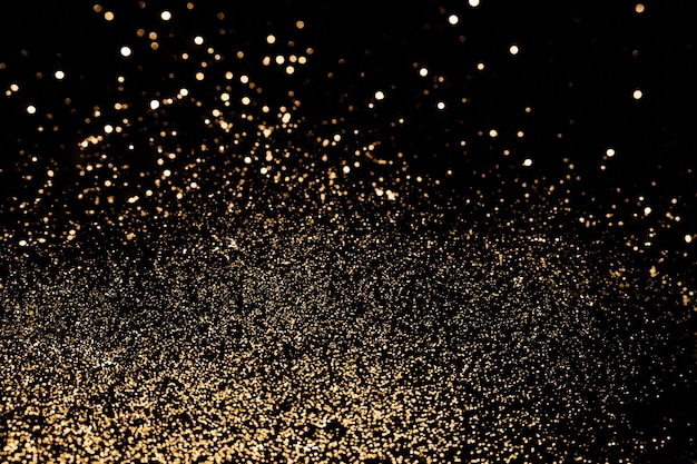 Fundo festivo preto Dispersão abstrata de brilhos de ouro no foco seletivo de pano de fundo preto de férias