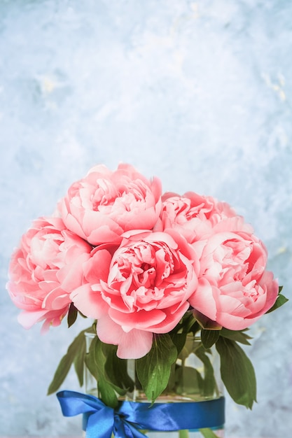 Fundo floral artístico. Buquê de flores de peônias rosa linda em um vaso de vidro. Grandes botões de peônias rosa