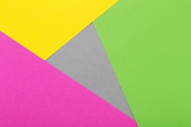 Fundo geométrico de folhas de papelão cinza, amarelo e verde e rosa