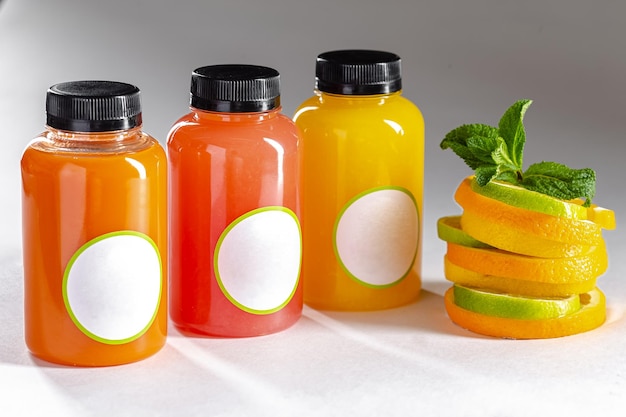 fundo isolado, garrafas de plástico com misturas de frutas e bagas, ao lado de fatias de limão, lima e