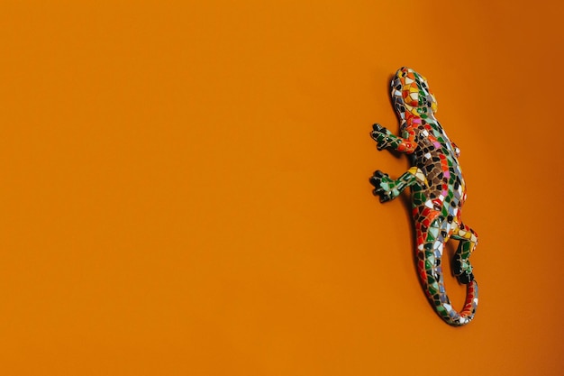 Fundo laranja e lagarto designer no canto esquerdo. Lagarto em um fundo laranja. Fundo brilhante íngreme. Salamandra.