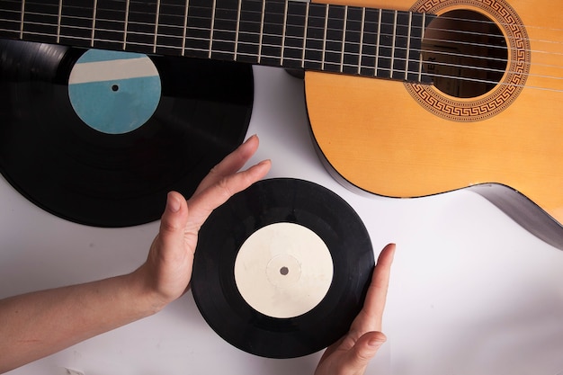 Fundo musical, guitarra e discos de vinil antigos em mãos femininas