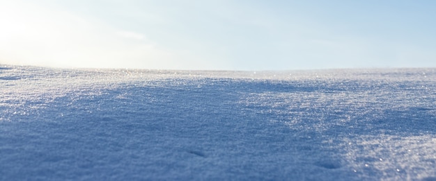 Fundo nevado, superfície nevada com uma textura claramente expressa de neve ao sol da manhã e céu ensolarado
