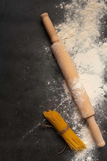 Fundo para assar com um rolo com farinha e macarrão Em uma mesa escura Espaço livre para texto