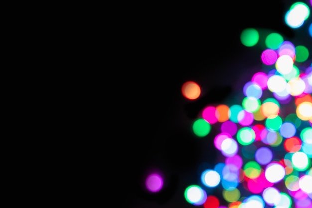 Foto fundo preto com luzes coloridas desfocadas no lado direito com efeito bokeh de espaço de cópia