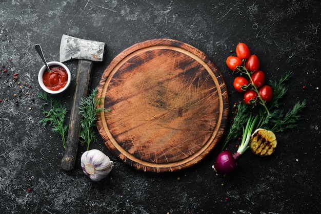 Fundo preto da cozinha Vegetais e especiarias da placa da cozinha em um fundo preto da pedra Vista superior