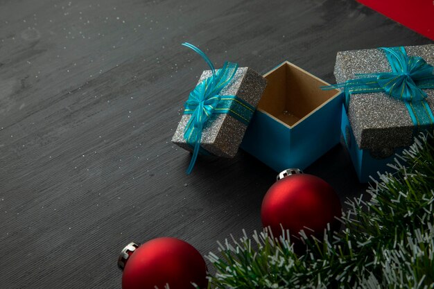 Fundo preto de madeira de natal com esferas vermelhas e presentes com laço azul