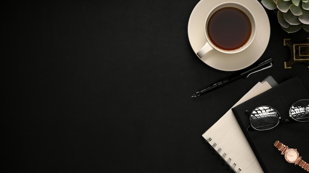 Fundo preto mínimo do espaço de trabalho com papelaria de xícara de café e espaço de cópia em cima