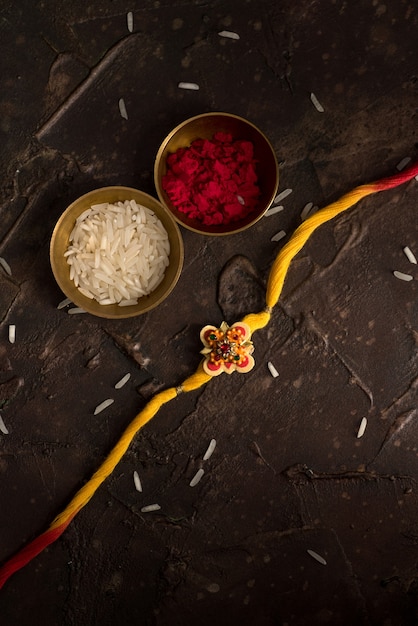 Fundo Raksha Bandhan com um elegante Rakhi, Grãos de Arroz e Kumkum