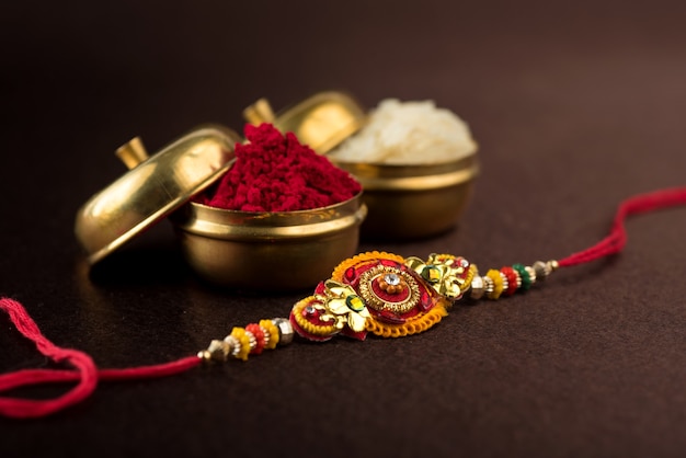 Fundo Raksha Bandhan com um elegante Rakhi, Grãos de Arroz e Kumkum