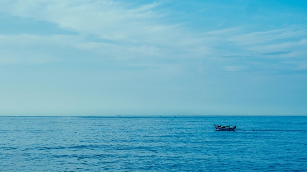 Fundo simples Barco de pesca de mar azul escuro calmo sozinho branco pálido Nuvens à deriva Caminho aberto sem limitações