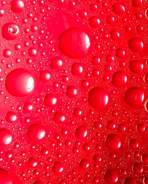 Fundo vermelho abstrato. Líquido no vidro. Gotas de água coloridas