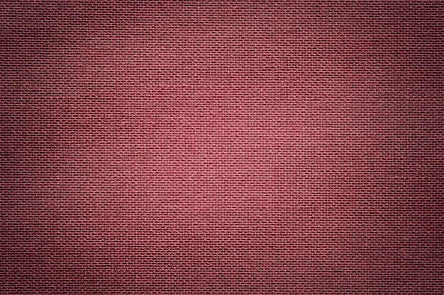 Fundo vermelho escuro de um material têxtil. Tecido com textura natural.
