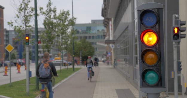 Funktionierende Ampel für Fahrräder im Vordergrund, Fahrradfahrer auf der Straße im Hintergrund