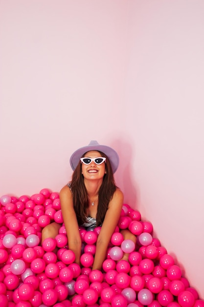 Funky bastante joven divirtiéndose en la piscina con globos de plástico rosa Concepto monocromático