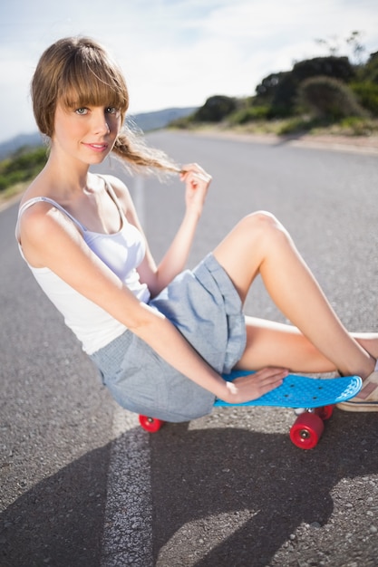 Funky joven rubia sentada en su patineta