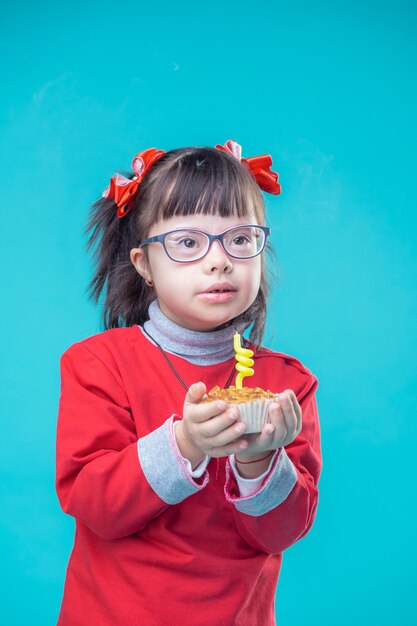 Funky Kerze löschen. Interessierte junge Dame mit klarer Brille und genauem Tragen des Kuchens mit beiden Händen