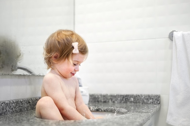 Funnycutecaucasian nacktes Baby Mädchen Kleinkind sitzen im Waschbecken Zähneputzen spielen in Badezimmergesundheit