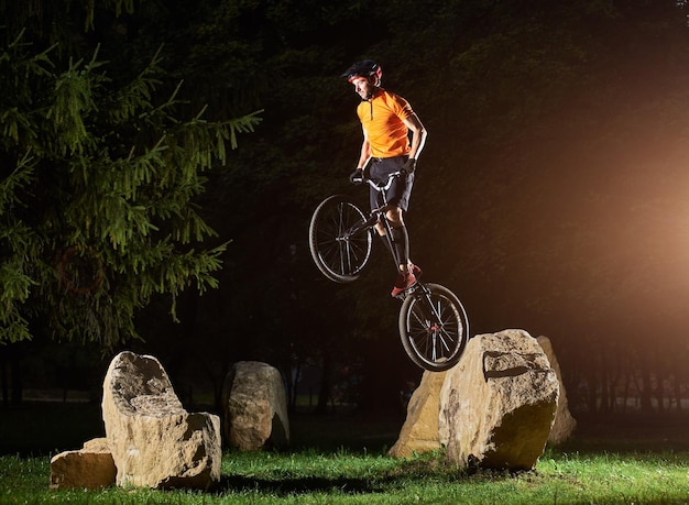 Furchtloser Kerl, der einen Trick macht, während er auf einem Fahrrad steht