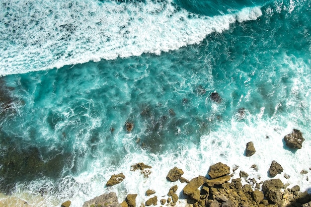 Foto furiosas olas azules del océano corren y se rompen en las rocas, vista superior