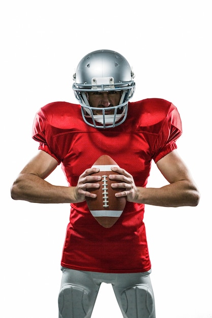 Furious jogador de futebol americano em jersey vermelho e capacete segurando bola