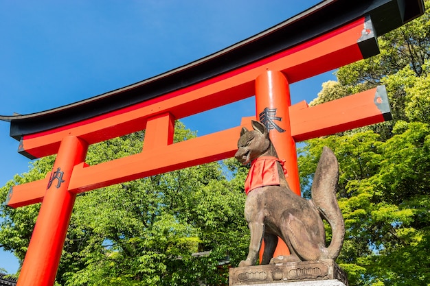 Fushimi inari stone fox guarda puertas de madera. Se cree que los zorros son mensajeros de dios.