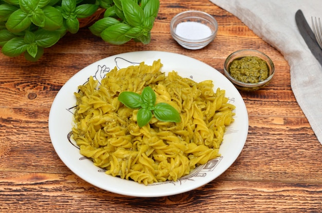 Fusilli-Nudeln mit Basilikum-Pesto-Sauce in einem Teller auf einem Tisch aus nächster Nähe