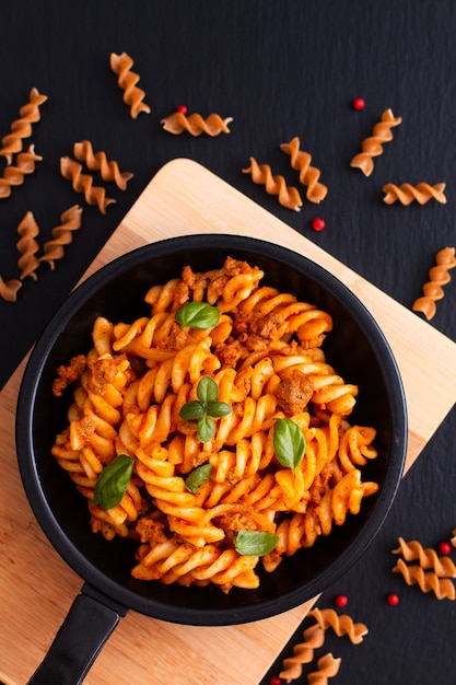 Fusilli-Teigwaren mit Soßen von Bolognese in der schwarzen Eisenpfanne