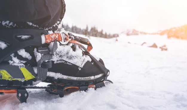 Fuß mit Steigeisen, das auf Schnee steht