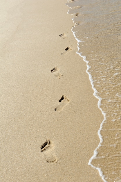 Fußabdrücke und Welle im Sand