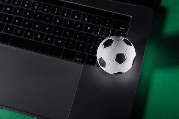 Fußball auf der Tastatur eines Laptops. Sport, Glücksspiel, Geldgewinnkonzept