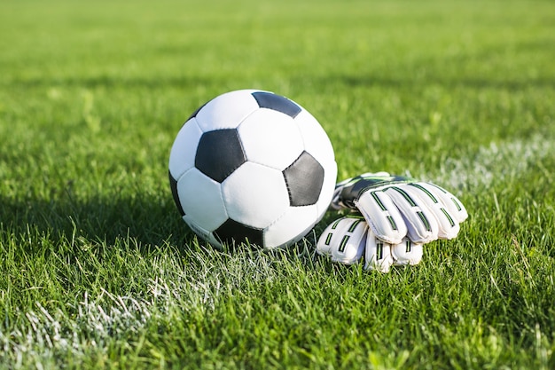 Foto fußball im gras neben handschuhen