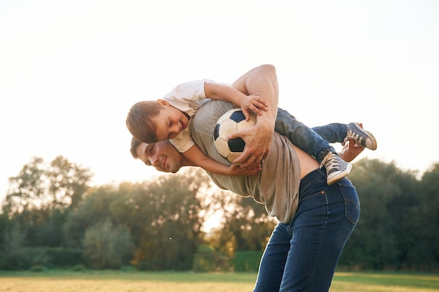 Fußball in den Händen Vater und kleiner Sohn spielen und haben Spaß im Freien
