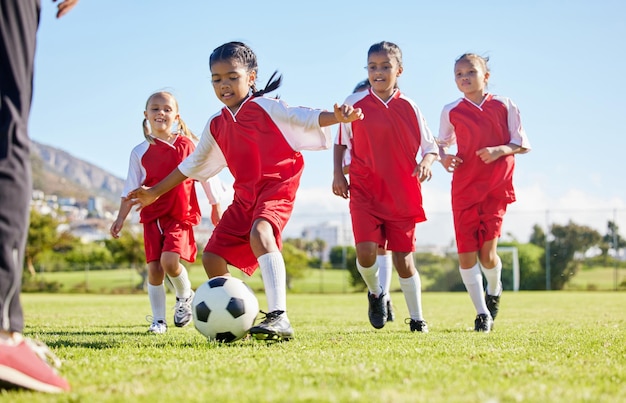 Fußball oder Sport und eine Mädchenmannschaft trainieren oder spielen zusammen auf einem Feld zum Üben Fitnessfußball und Gras mit Kindern, die auf einem Spielfeld für Wettkämpfe oder Übungen laufen oder dribbeln