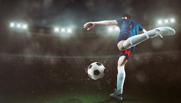 Fußball-Szene bei Nacht Match mit Spieler, der den Ball mit Kraft tritt