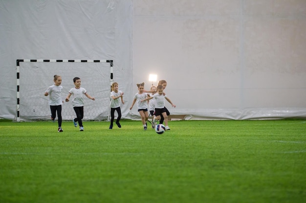 Fußballarena drinnen Kindermannschaft, die Fußball spielt