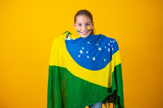 Fußballfan, brasilianisches Team. Schönes kleines Mädchen jubelt für ihr Team auf gelbem Hintergrund