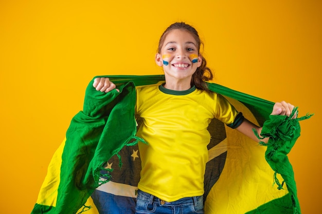 Fußballfan, brasilianisches Team. Schönes kleines Mädchen jubelt für ihr Team auf gelbem Hintergrund