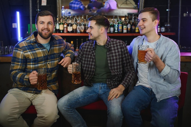 Fußballfans an der Bar Fröhliche Fußballfans jubeln an der Bar und trinken Bier, während der Barkeeper im Hintergrund Bier serviert