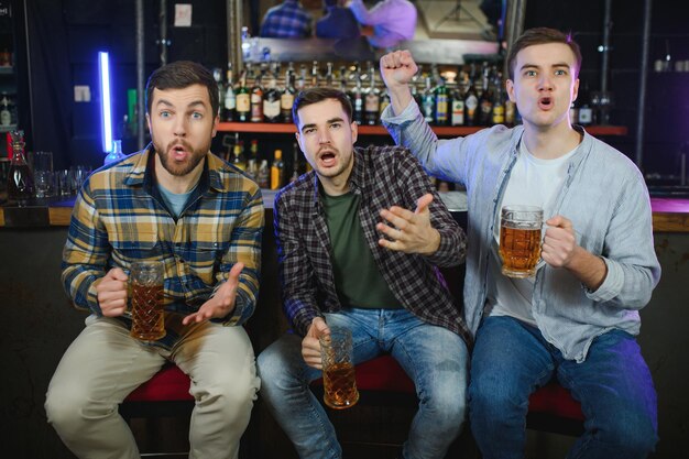 Fußballfans an der Bar Fröhliche Fußballfans jubeln an der Bar und trinken Bier, während der Barkeeper im Hintergrund Bier serviert