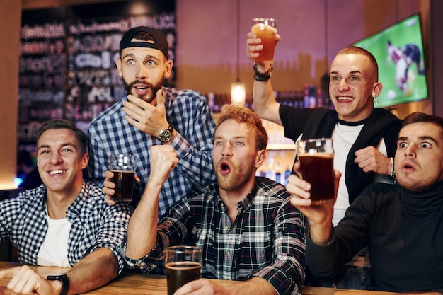 Fußballfans, die fernsehen Gruppe von Menschen, die drinnen in der Kneipe zusammen sind, haben am Wochenende Spaß