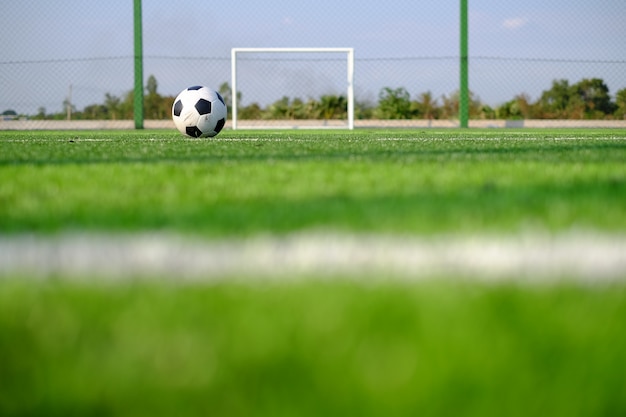 Fußballfußball auf grüner Rasenfläche und Torpfosten