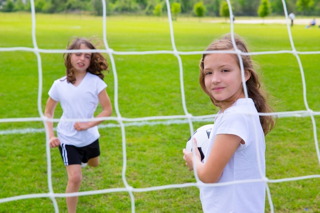 Fußballfußballkindermädchen, die auf Feld spielen