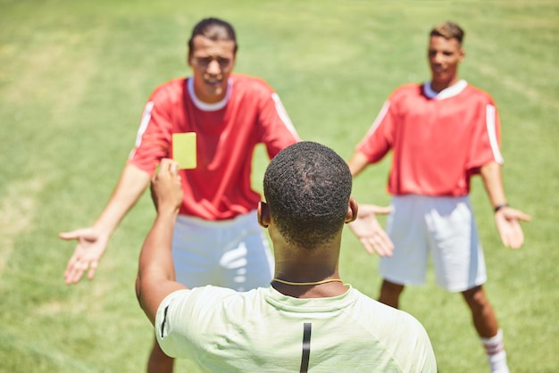 Fußballmannschaft und Schiedsrichter mit Buchung der gelben Karte und Foul an einem Spieler auf einem Rasenplatz oder -feld während eines Spiels Fitness-Fußball und Disziplin mit einem Schiedsrichter, der während eines Sportspiels eine Verwarnung gibt